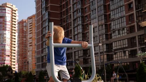 A Small Boy Trains on a Modern Simulator on a Sports Field in the Courtyard
