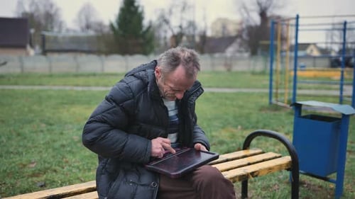 Senior Man Using Tablet on Park Bench