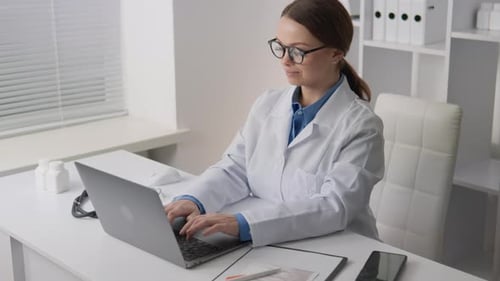 Woman Doctor Working on Laptop in Clean Office