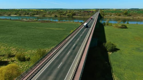 Cargo Truck with White Semi Trailer Driving Across Bridge Through Green Countryside Freight