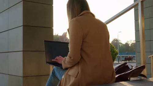 Mulher sentada na escada na rua da cidade e usando o laptop