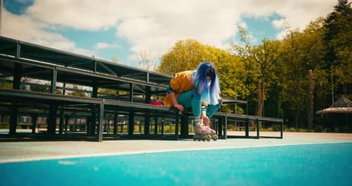 Teenager Roller Skater Girl with Blue Hair Puts on Rollerblades at Skate Park Training Hobby Active