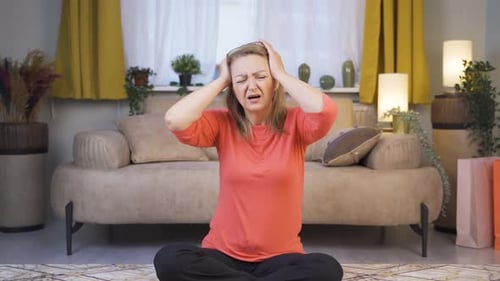 Woman with Headache Sitting on Floor in Living Room