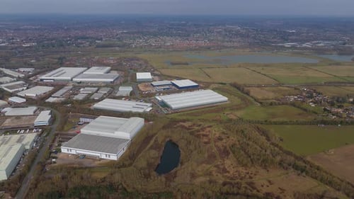 Aerial footage of an industrial complex filled with huge distribution warehouses and rows of trucks.
