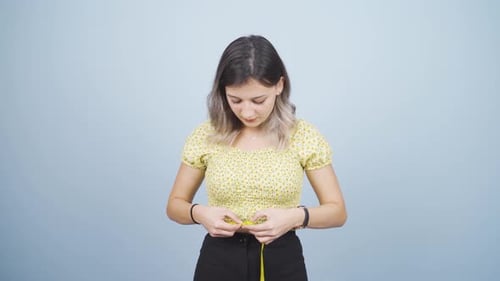 Persona infeliz que mide su peso con una cinta métrica.