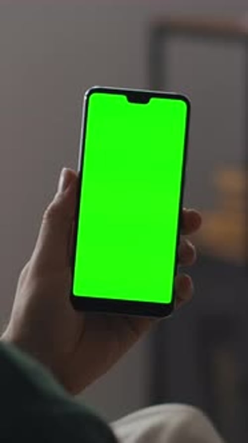 Closeup of a Person Holding a Modern Smartphone with a Bright Green Chroma Key Display Screen in a