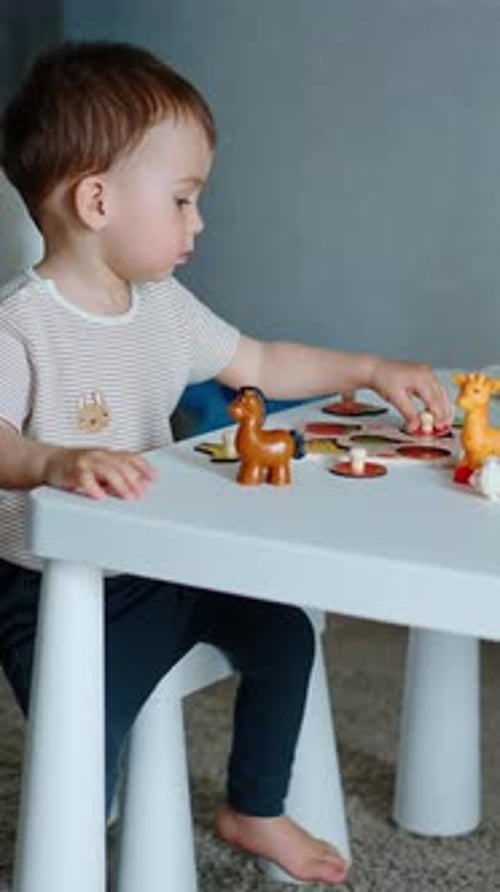 Kaukasisches Kind, das mit Spielzeugtieren spielt und mit Obst spielt. Kleines Baby spielt am Schreibtisch.
