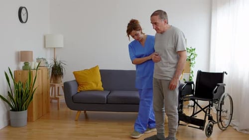 Young Adult Nursing Home Helping Older Man to Move at Domestic Room