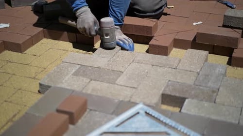 Bricklayer Installing Colorful Pavement Bricks with Mallet