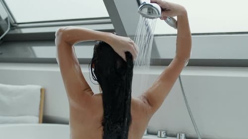 Woman Shampooing Long Dark Hair in Modern Bathroom