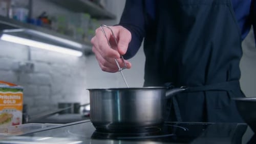 Chef Stirring Sauce in Restaurant Kitchen