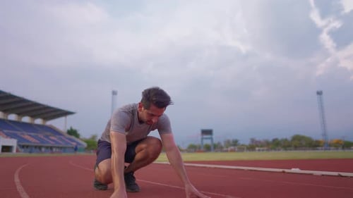 Kaukasischer junger Sportler, der auf einer Strecke im Stadion trainiert.