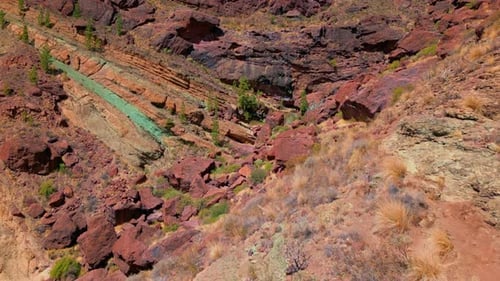 Drohnenschuss aus der Luft, der vorwärts über die leuchtend grünen und roten vulkanischen Mineralschichten des Los flog