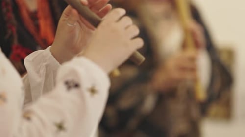 Eine Frau spielt eine Holzpfeife im Kreis der Musiker