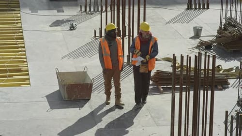 Construction Workers Discussing Blueprints on Site