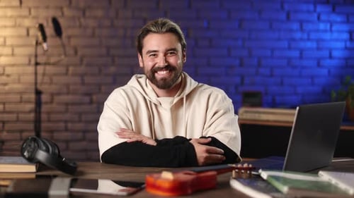 Smiling Man at Desk with Tech and Music Gear