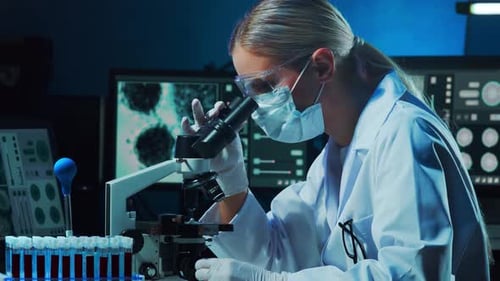Woman Scientist Uses Microscope in a Dark Laboratory