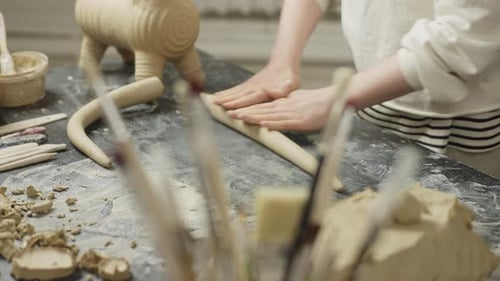 Woman Sculpting Clay Figure in Pottery Studio