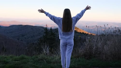 Free Woman Raising Her Arms Towards Mountain Sunset