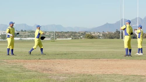 Raising glove, diverse male teammates practicing catch-and-throw drill in outfield, with baseballs