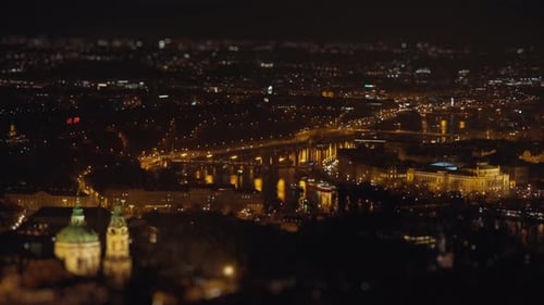 Prague at night - dim street lights on the quay and traffic on the streets and bridges. Aerial view,