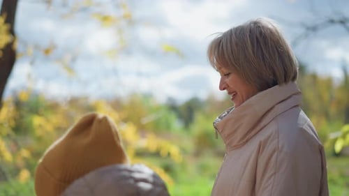 Aunt Walking with Kid in Autumn Forest As Sunlight Filters Through Trees