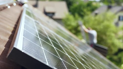 Technician PV professional climbs lader carrying solar panel to install