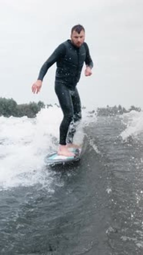 Adult Man Wake Surfing on Water on Overcast Day