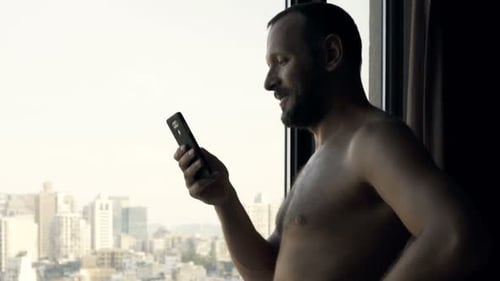 Man Using Smartphone in High Rise Apartment