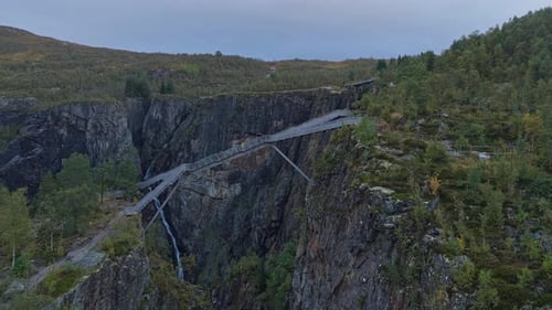 Cinematic drone sweep across Voringfossen waterfall and forested gorge