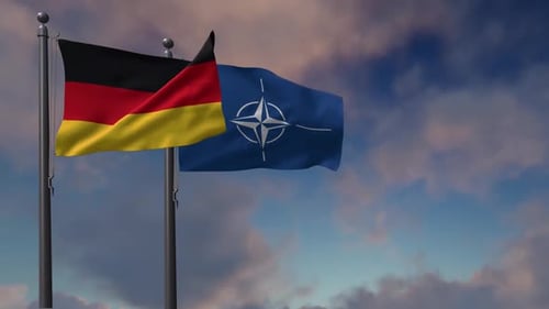 German and NATO Flags Waving Against a Cloudy Sky