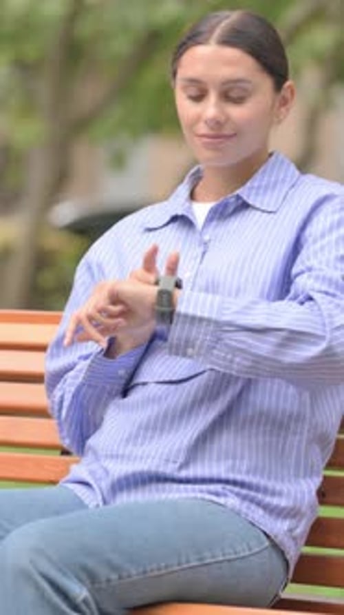 Woman Sitting on Bench Using Smart Watch