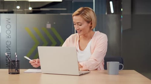 Woman Types on Laptop and Takes Notes at Desk