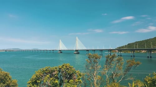 Drone: vista lateral aérea de uma ponte estaiada de concreto sobre o oceano tropical de cor turquesa, lo