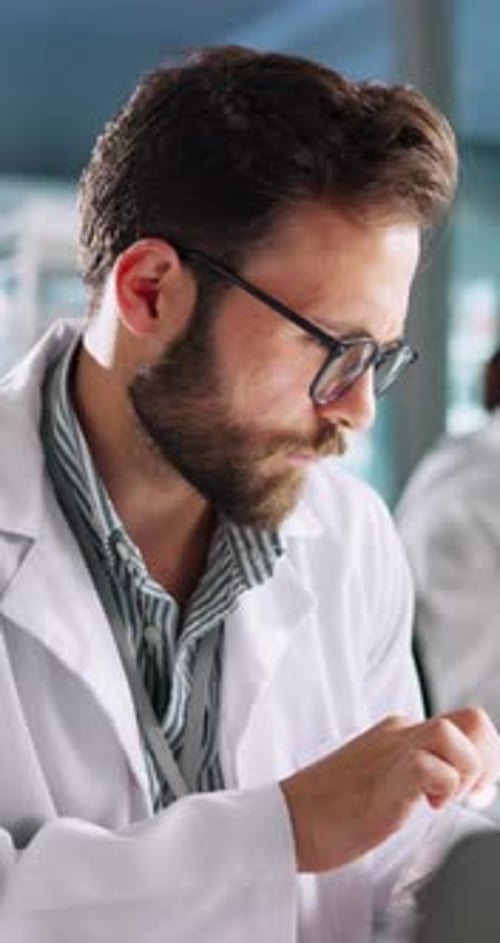 Médecin, homme et ordinateur portable en laboratoire avec tablette, recherche et sourire pour la résolution de problèmes