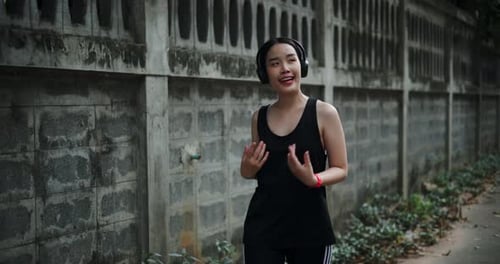 A young woman walks for exercise, enjoying the nice atmosphere on the sidewalk.