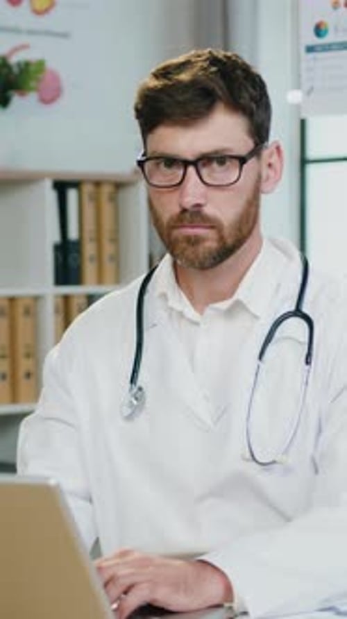 Doctor Working on Laptop at Desk Smiling Portrait