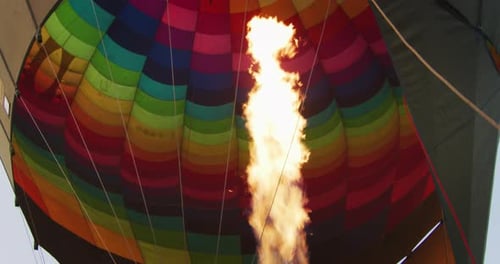Slow motion close up view of the flame inside of a colorful hot air balloon being inflated before
