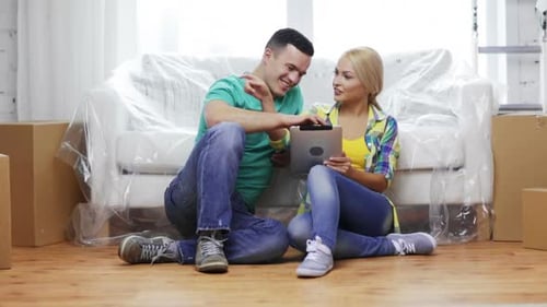 Couple using tablet on floor in new home