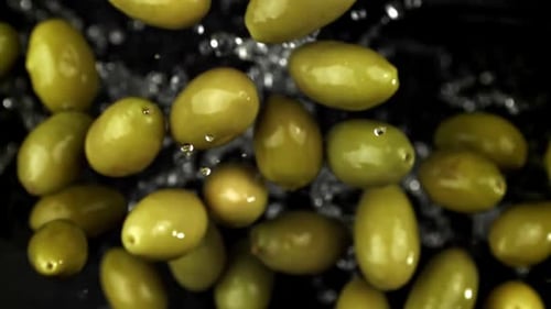 Green Olives Floating on Black Background with Water