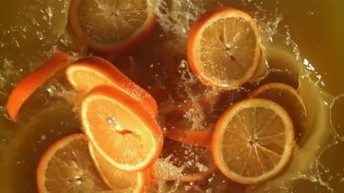 Orange Slices Falling into Orange Juice