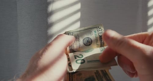 Close Up of Hands Counting Twenty Dollar Bills