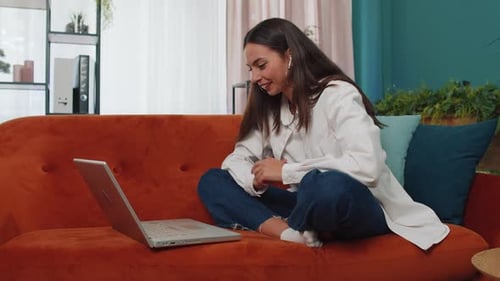 Smiling Woman Video Chats on Laptop at Home