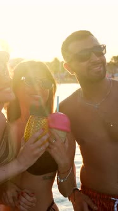 Friends Enjoying Tropical Cocktails at Sunset Beach Party