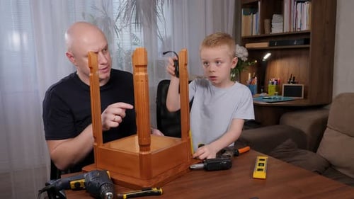 A Little Boy and His Father are Repairing or Assembling a Chair at Home