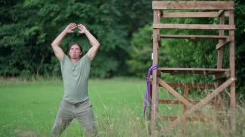 A Man is Practicing Physical Activities Near a Wooden Structure in a Natural Setting Slow Motion