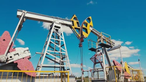 Pumpjacks operieren auf einem Ölfeld vor dem Himmel mit weißen Wolken