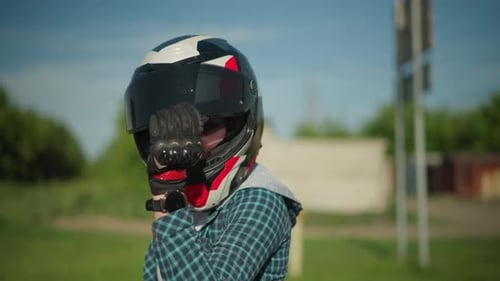 Female Biker Adjusting Helmet Visor with Gloved Hand Outdoors
