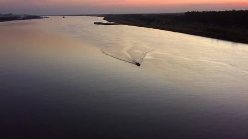 Small motorboat traveling across the Paraguay River at sunset.