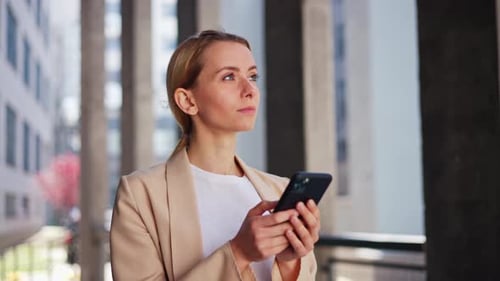 Woman With Phone Standing in an Urban Setting
